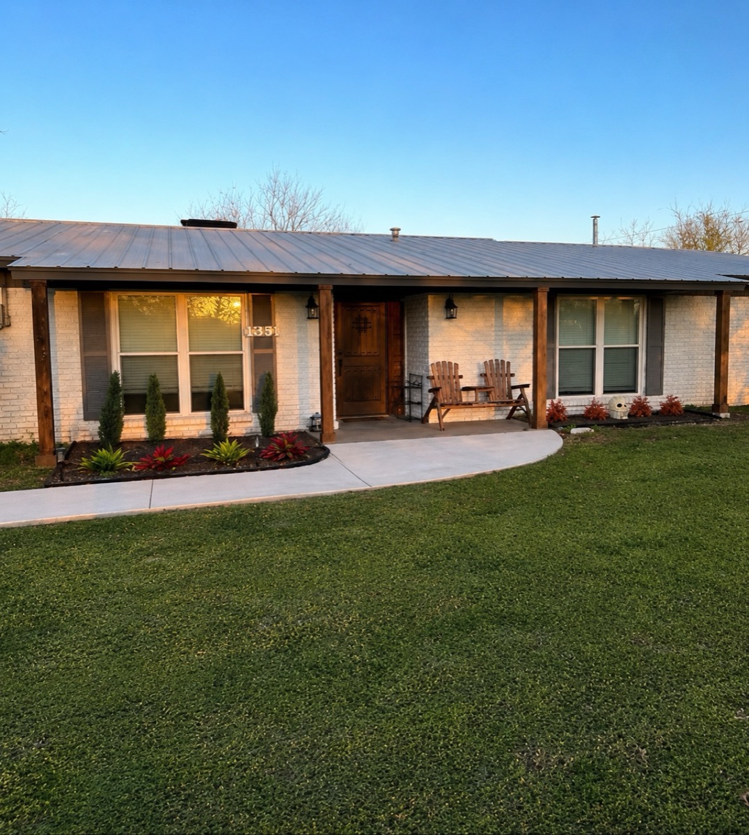 Remodeled ranch house exterior with cedar posts, landscaping, and curved walkway